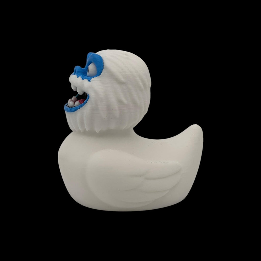Three views of a white 3D printed Yeti duck showing its blue face and side profiles.