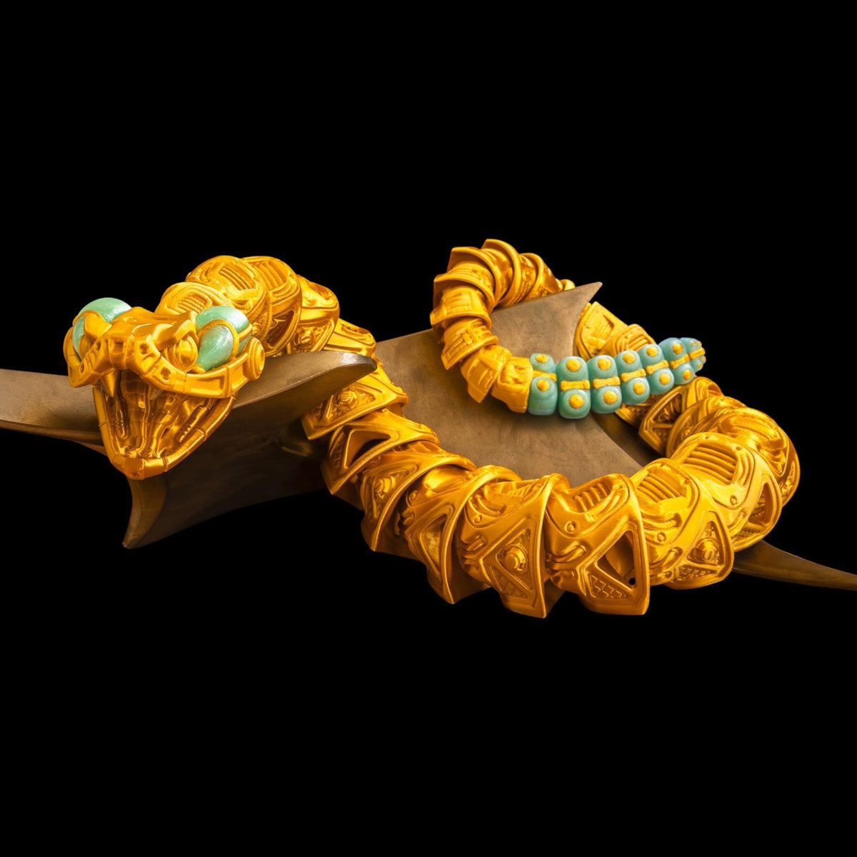 Gold and green 3D printed Robo-Rattler snake in a curved pose, showing its jointed body.