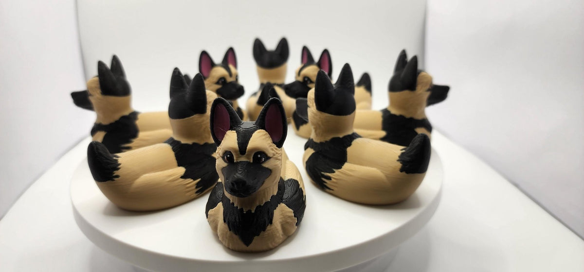 Group of 3D printed German Shepherd ducks showing front, side and rear views on a white display. - JM Designs