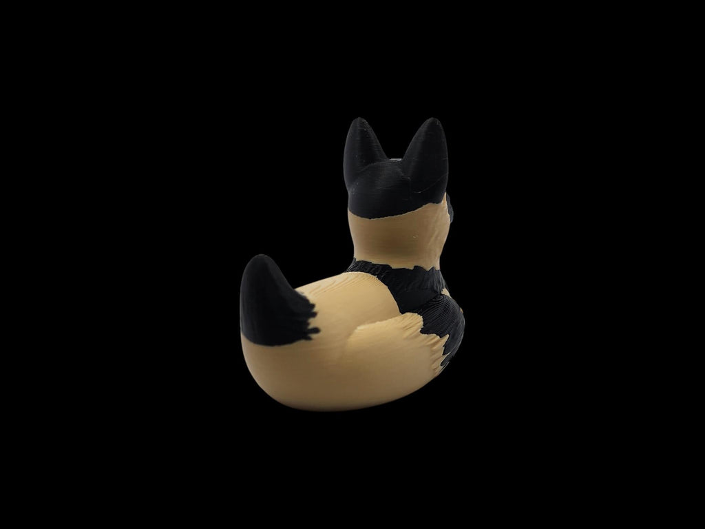 Angled rear view of a black and tan 3D printed German Shepherd duck with its raised tail on the left.- JM Designs