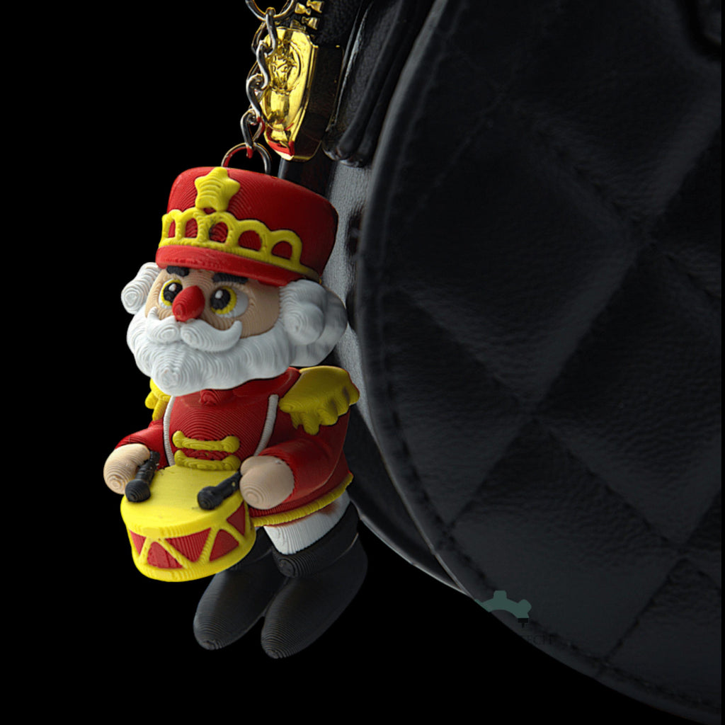 Miniature Collectible Nutcracker Articulated Santa Figure Christmas Keychain Holiday Decoration Festive Character Design Movable Arms Posable Creation Premium Material Construction Red Yellow Uniform Crown Hat White Beard Small Drum Detail