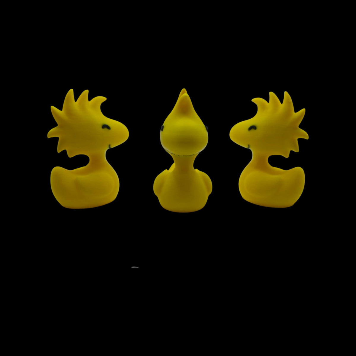 Three yellow Woodstock duck figurines are shown from slightly different angles, with the center one facing forward