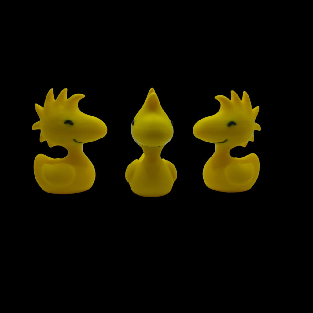 Three yellow Woodstock duck figurines are arranged in a row, with the center one facing forward and the outer two facing