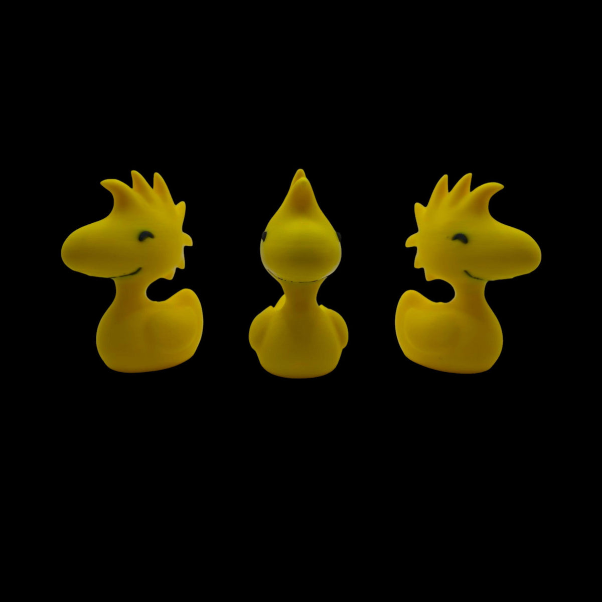 Three yellow Woodstock duck figurines are shown from slightly different angles, with the center one facing